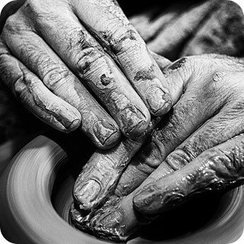 A close up of a potters hands making something from clay.